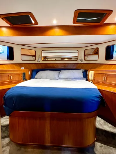  Yacht Photos Pics Luxurious bedroom interior of a 1996 Fleming 55 yacht with wood paneling and blue bedding.