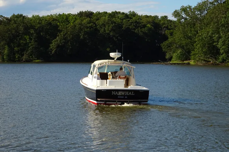 Narwhal Yacht Photos Pics 2007 Hunt Yachts Surfhunter 29 cruising on a serene lake with lush forest backdrop.