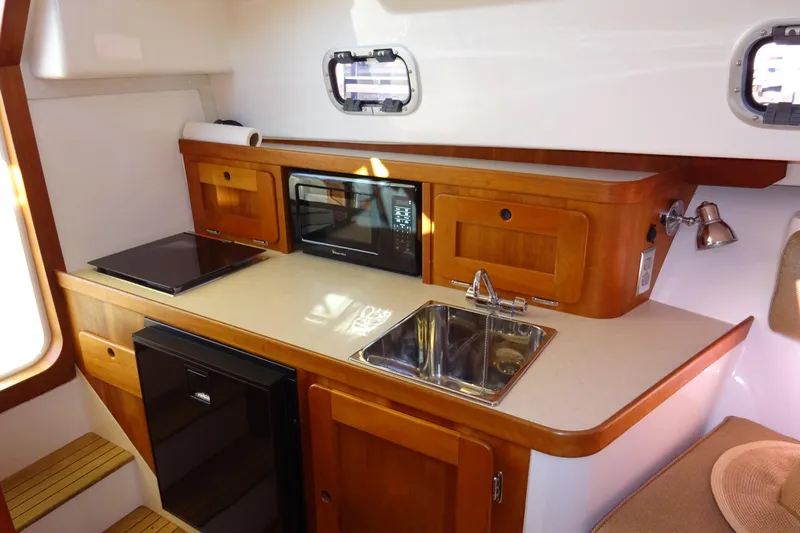 Narwhal Yacht Photos Pics 2007 Hunt Yachts Surfhunter 29 interior kitchen with sink, microwave, and wooden cabinetry.