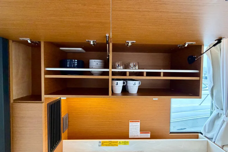  Yacht Photos Pics Interior of 2026 Beneteau Swift Trawler 41 Fly with open wooden cabinets displaying dishes.