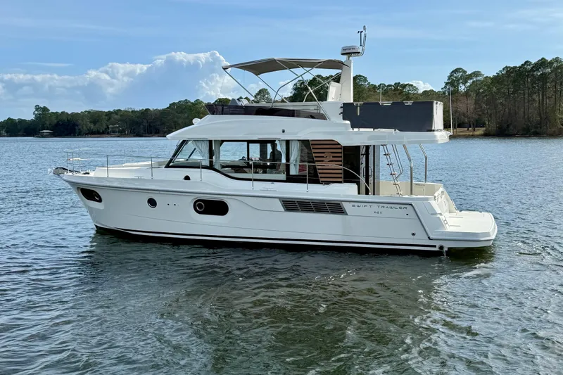  Yacht Photos Pics 2026 Beneteau Swift Trawler 41 Fly on serene lake with trees in background.