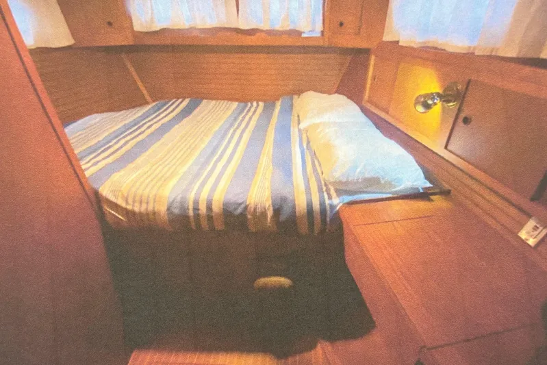 Latte Yacht Photos Pics Cozy cabin interior of 1987 Nauticat 38 sailboat with striped bedding and wooden furnishings.