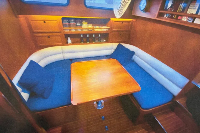 Latte Yacht Photos Pics Cozy interior of 1987 Nauticat 38 sailboat with wooden table and cushioned seating.