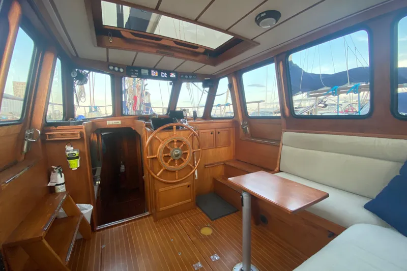 Latte Yacht Photos Pics Interior of 1987 Nauticat 38 sailboat with wooden helm and seating area.