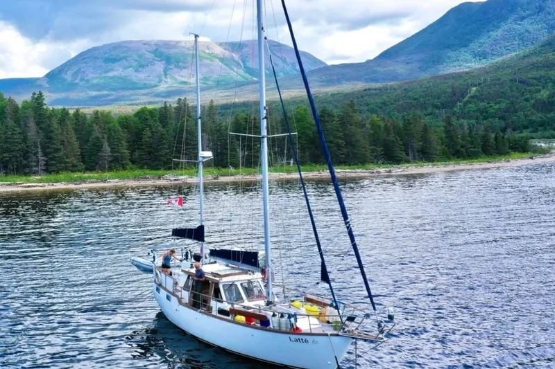 Latte Yacht Photos Pics Sailboat Nauticat 38 (1987) on scenic lake with forested mountains in background.