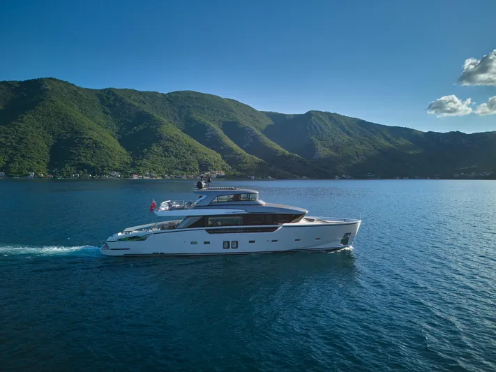  Yacht Photos Pics Sanlorenzo SX88 2020 yacht cruising on blue water with lush green mountains in the background.