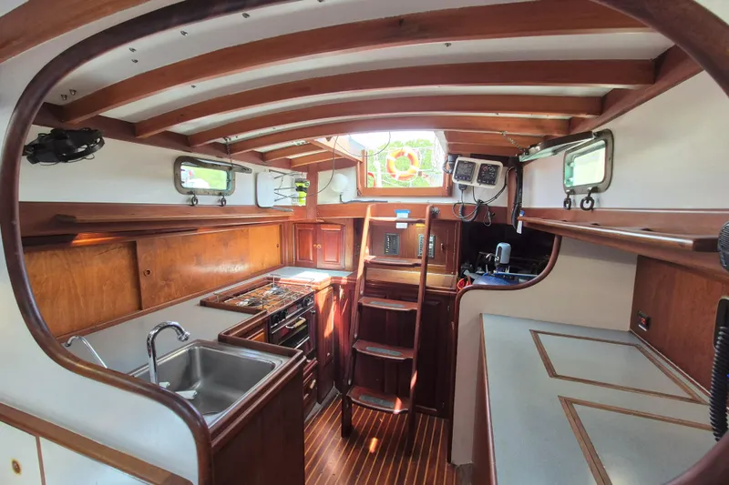 Pearl Yacht Photos Pics Interior of a 1996 Cape George 36 sailboat with wooden cabinetry and compact kitchen.