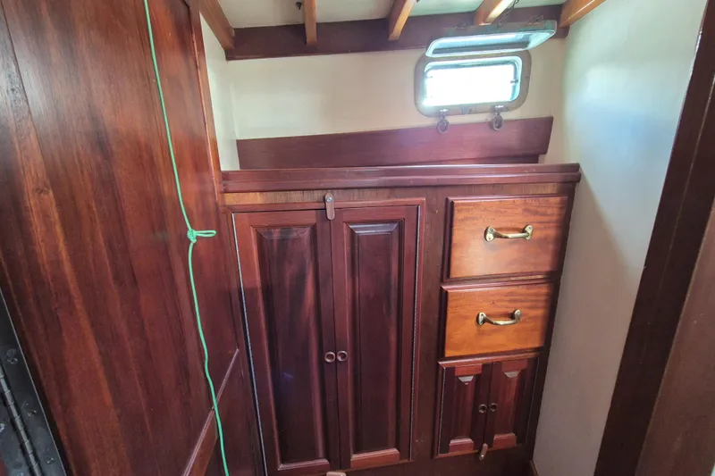 Pearl Yacht Photos Pics Wooden interior cabinetry on a 1996 Cape George 36 sailboat, featuring brass handles and a small window.