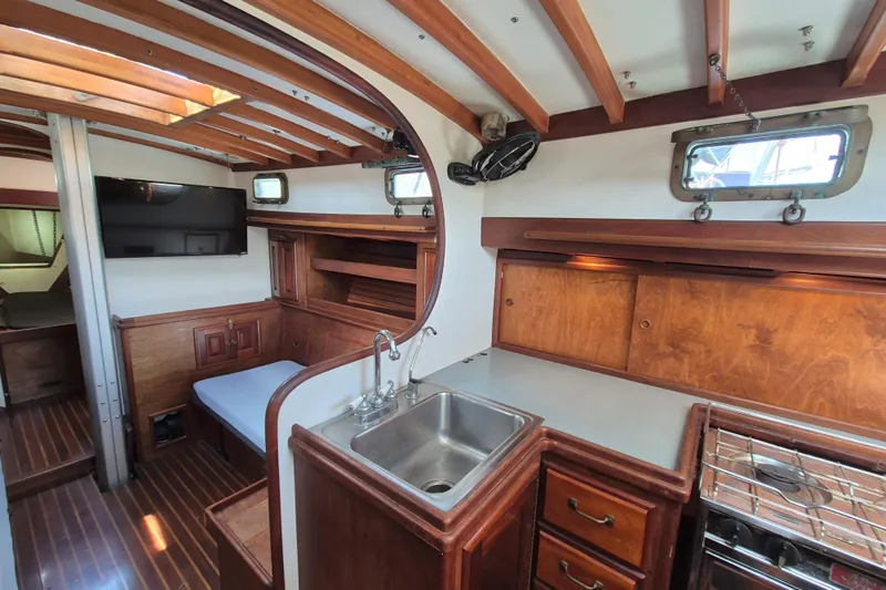 Pearl Yacht Photos Pics Interior of a 1996 Cape George 36 sailboat with wooden cabinetry and compact kitchen.