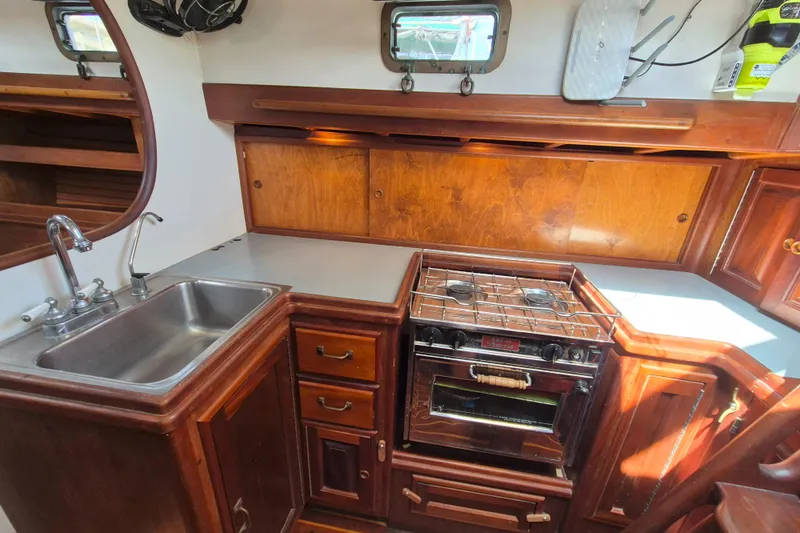 Pearl Yacht Photos Pics Cozy 1996 Cape George 36 yacht kitchen with wood cabinetry, stove, and sink.