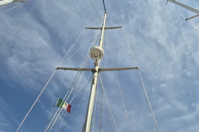 Pearl Yacht Photos Pics Mast of 1996 Cape George 36 sailboat with Mexican flag against cloudy sky.
