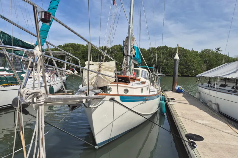 Pearl Yacht Photos Pics 1996 Cape George 36 sailboat docked in a marina, surrounded by calm water and greenery.
