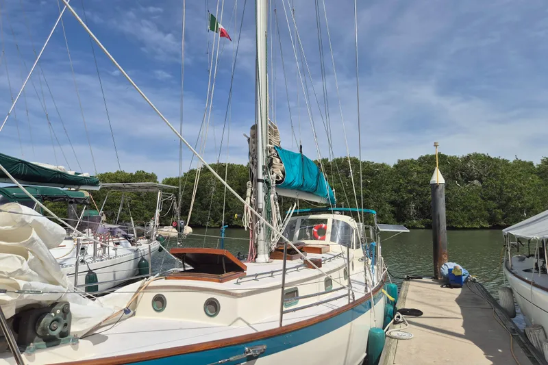 Pearl Yacht Photos Pics Cape George 36 sailboat docked, 1996 model, with lush greenery and clear sky background.