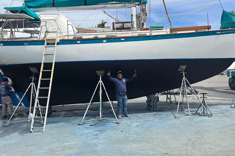 Pearl Yacht Photos Pics Man standing under a 1996 Cape George 36 sailboat on a dry dock with ladders.