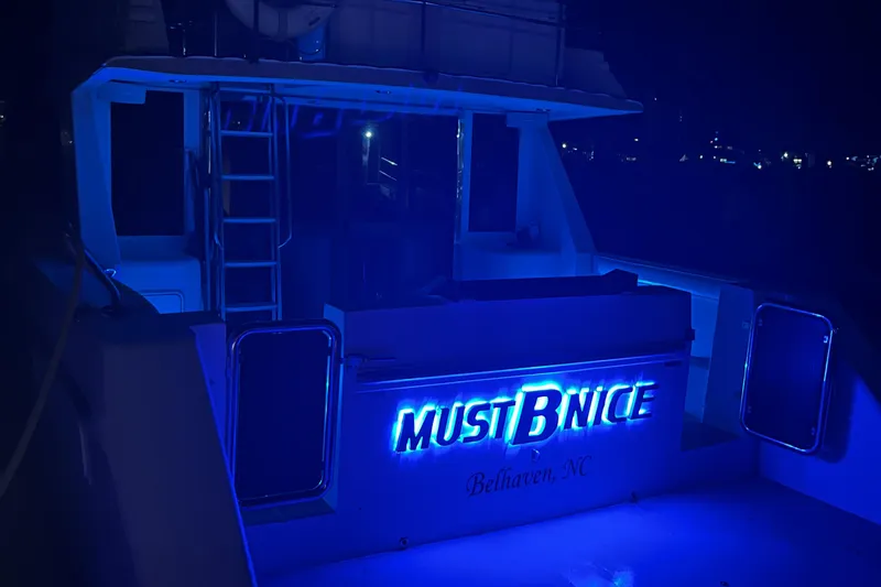 Must B Nice Yacht Photos Pics Custom Sports Catamaran 44, 2001, illuminated at night with blue lights, "Must B Nice" signage.