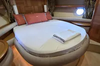 Luxurious bedroom interior of 2011 Azimut 55 EVOLUTION yacht with round bed and porthole.