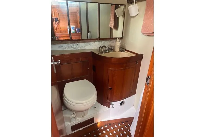 Pickle Yacht Photos Pics 1989 Hylas 44 yacht bathroom with wooden cabinetry and mirrored storage.