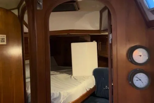 Pickle Yacht Photos Pics Interior cabin of a 1989 Hylas 44 yacht with wooden finishes and cozy bedding.