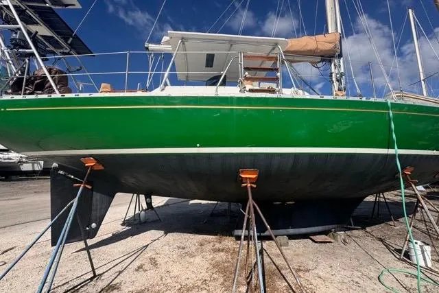 Pickle Yacht Photos Pics Green 1989 Hylas 44 sailboat on dry dock, supported by stands, under a clear blue sky.