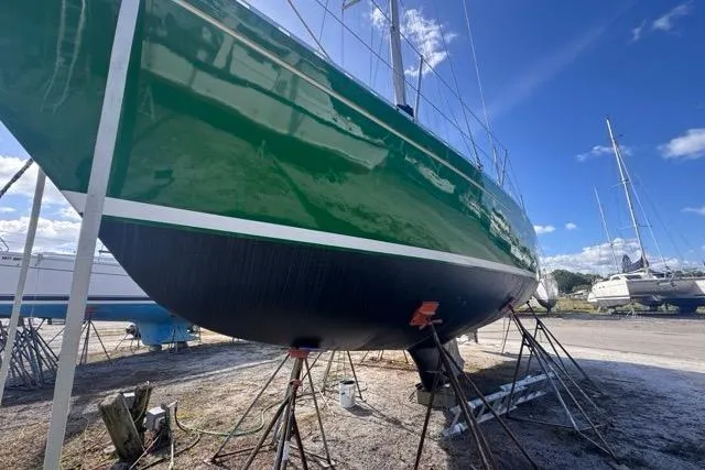 Pickle Yacht Photos Pics Green 1989 Hylas 44 sailboat on stands, clear sky background.