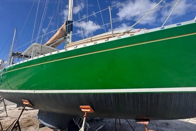 Pickle Yacht Photos Pics Green 1989 Hylas 44 sailboat on stands, clear sky background.