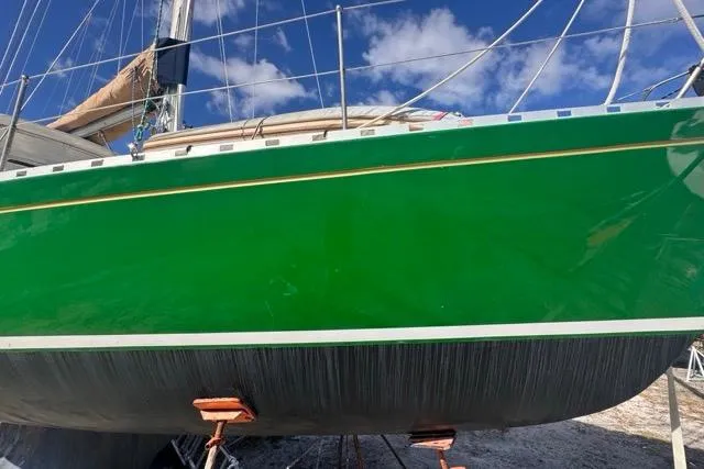 Pickle Yacht Photos Pics Green 1989 Hylas 44 sailboat hull on stands, clear sky background.