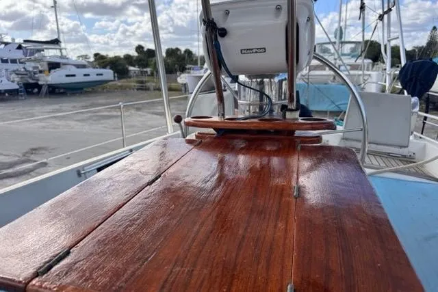 Pickle Yacht Photos Pics Polished wooden deck of 1989 Hylas 44 sailboat with marina background.