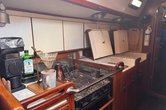 Pickle Yacht Photos Pics 1989 Hylas 44 yacht kitchen with stove, coffee maker, and wooden cabinetry.