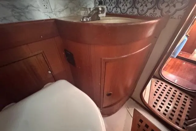 Pickle Yacht Photos Pics Wooden bathroom interior of 1989 Hylas 44 yacht with sink and patterned wall.