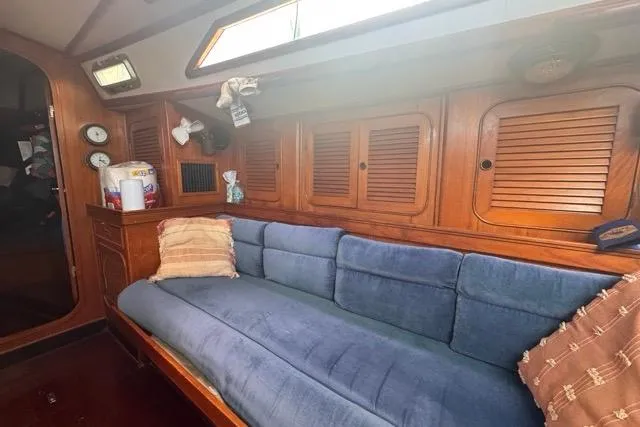Pickle Yacht Photos Pics 1989 Hylas 44 yacht interior with blue sofa and wooden cabinets.