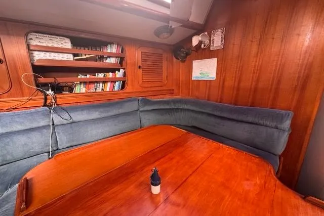 Pickle Yacht Photos Pics Cozy interior of 1989 Hylas 44 sailboat with wooden table and bookshelf.