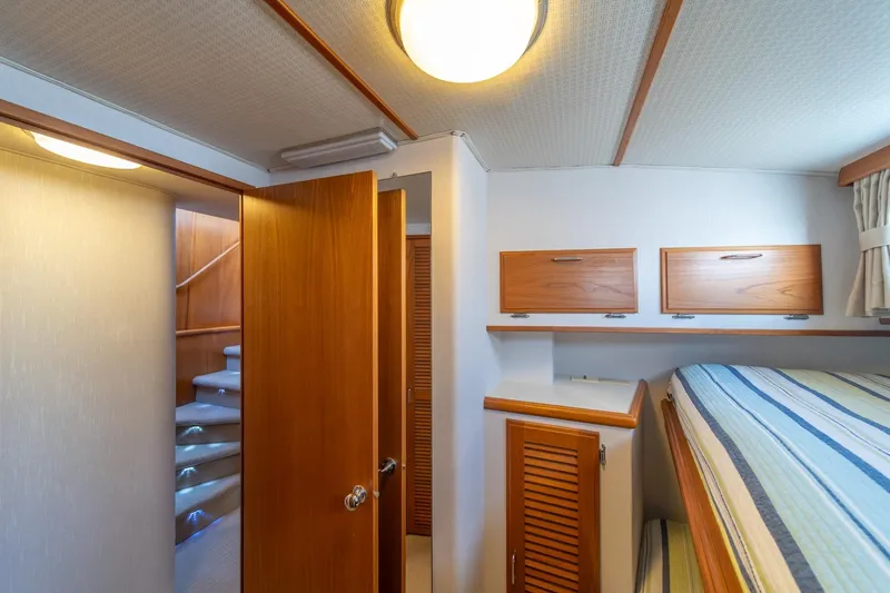 Sumo Yacht Photos Pics 1991 Tollycraft 57 Pilothouse Motor Yacht interior cabin with wooden accents and striped bedding.