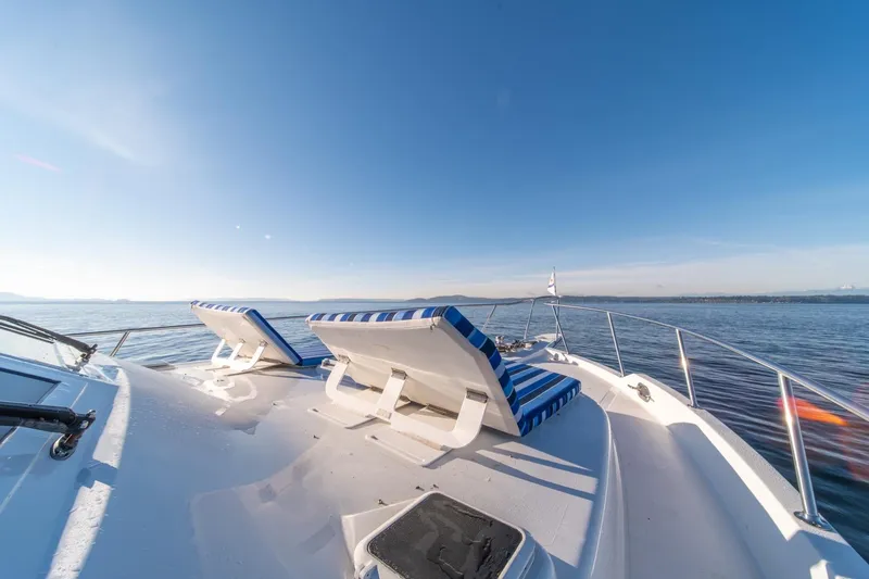Sumo Yacht Photos Pics 1991 Tollycraft 57 Pilothouse Motor Yacht deck with striped lounge chairs on open water.