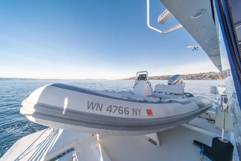 Sumo Yacht Photos Pics 1991 Tollycraft 57 Pilothouse Motor Yacht with inflatable boat on deck, scenic water view.