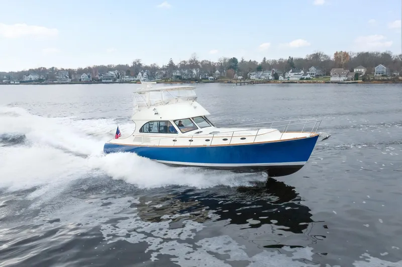 Sapphire II Yacht Photos Pics 2006 Hinckley Talaria 55 FB cruising on a calm lake near a residential shoreline.