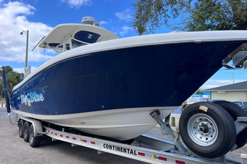 Big Blue Yacht Photos Pics 2017 Century 3200 Center Console boat on trailer, blue hull, parked outdoors.