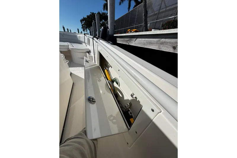  Yacht Photos Pics 2015 Edgewater 320CC boat with open storage compartment, docked under clear blue sky.