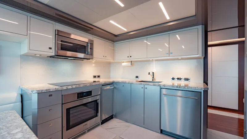 Pinch Me Yacht Photos Pics Modern kitchen interior on 2021 Ocean Alexander 28R yacht, featuring sleek cabinetry and stainless steel appliances.