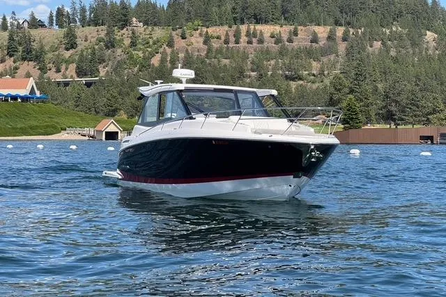  Yacht Photos Pics 2021 Regal 36 Grande Coupe on a scenic lake with forested hills.