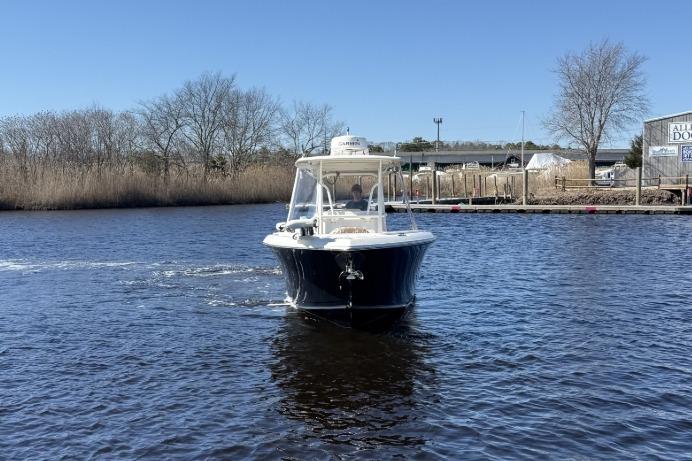 2015 Sailfish 2860 CC boat cruising on a calm river under a clear blue sky.