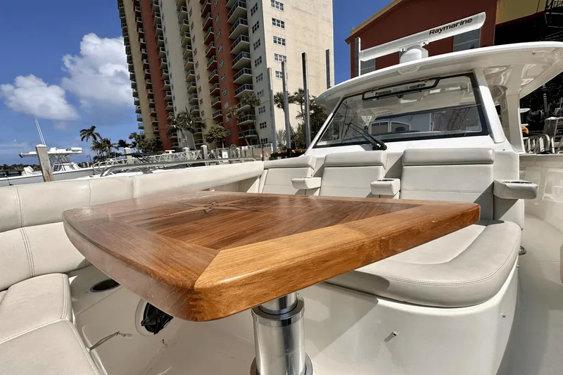  Yacht Photos Pics 2019 Boston Whaler 350 Realm boat with wooden table and seating, docked near tall buildings.