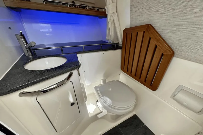  Yacht Photos Pics 2019 Boston Whaler 350 Realm boat bathroom with sink, toilet, and wooden seat cover.