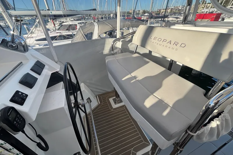  Yacht Photos Pics Helm station of 2022 Leopard 42 catamaran with steering wheel and cushioned seating.