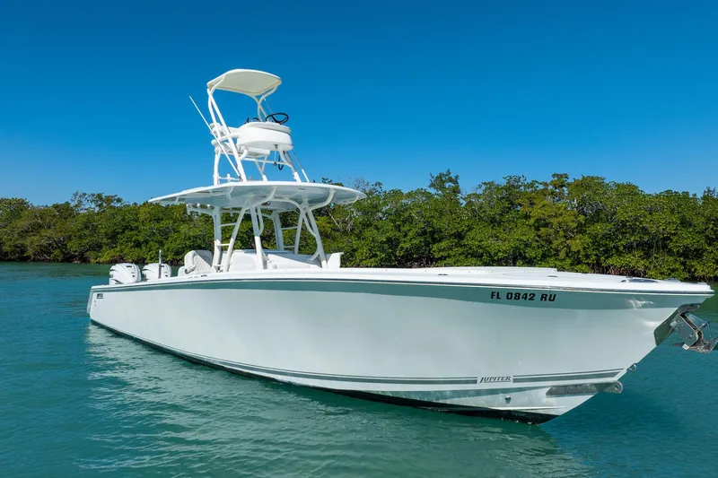  Yacht Photos Pics 2019 Jupiter 38 HFS boat on clear water, surrounded by lush greenery.