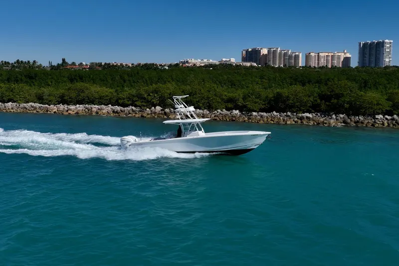  Yacht Photos Pics 2019 Jupiter 38 HFS boat cruising on turquoise water near a lush shoreline and cityscape.