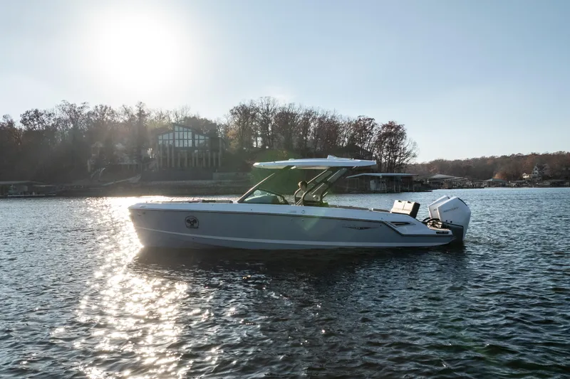  Yacht Photos Pics 2026 Monterey Elite 30 OB boat on a sunny lake, surrounded by trees and houses.