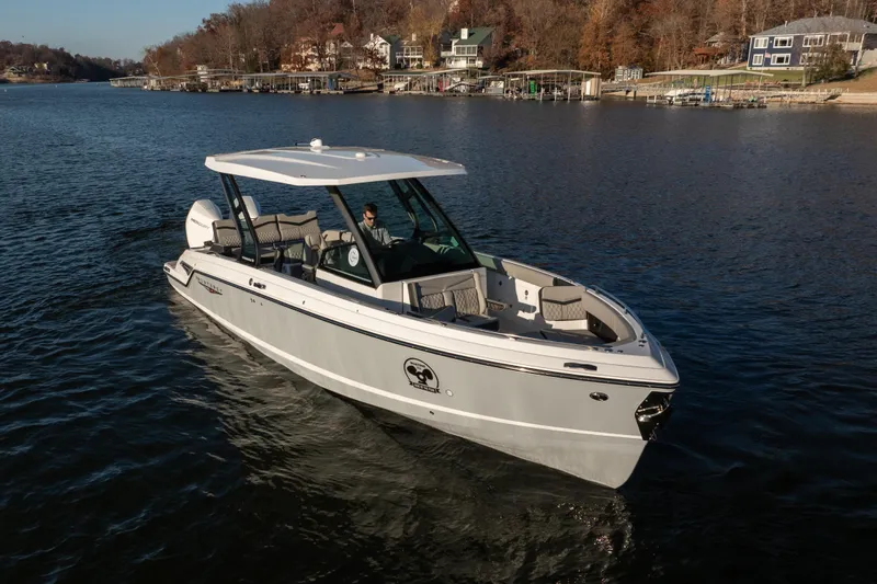  Yacht Photos Pics 2026 Monterey Elite 30 OB boat cruising on a serene lake with scenic shoreline.
