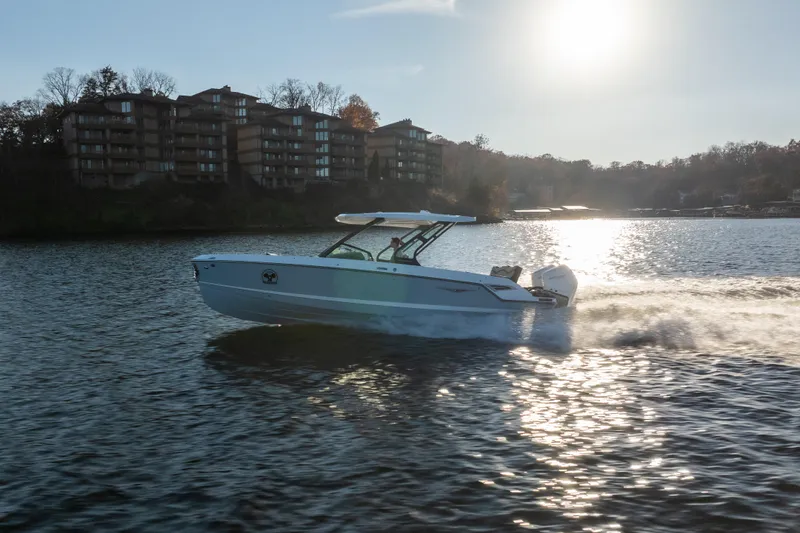  Yacht Photos Pics 2026 Monterey Elite 30 OB boat cruising on a sunlit lake near waterfront buildings.