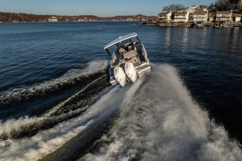  Yacht Photos Pics 2026 Monterey Elite 30 OB boat cruising on a scenic lake near waterfront homes.