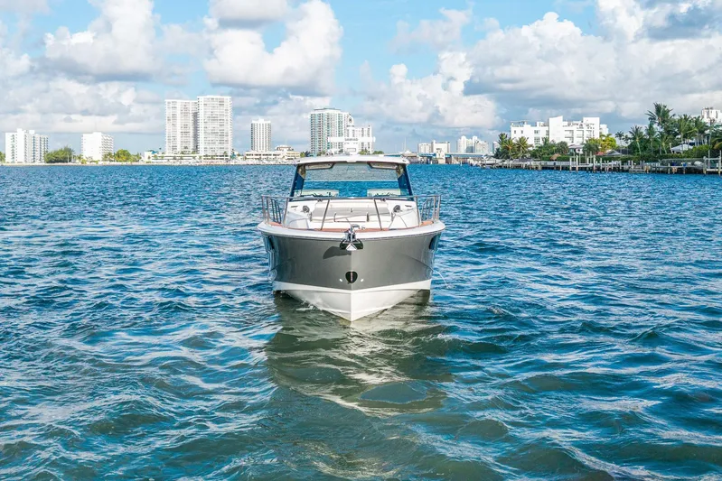  Yacht Photos Pics 2024 Boston Whaler 405 Conquest cruising on a sunny day with city skyline backdrop.